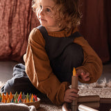 Young girl placing Grapat Baby Stick into a cardboard tube on the floor.