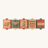 a row of the cardboard boxes for the different Grapat christmas decoration sets on a cream background