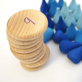 Stack of Grapat Counting Coins next to a pile of blue Grapat water drop mandala pieces.