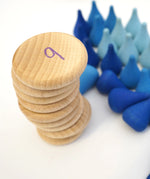 Stack of Grapat Counting Coins next to a pile of blue Grapat water drop mandala pieces.