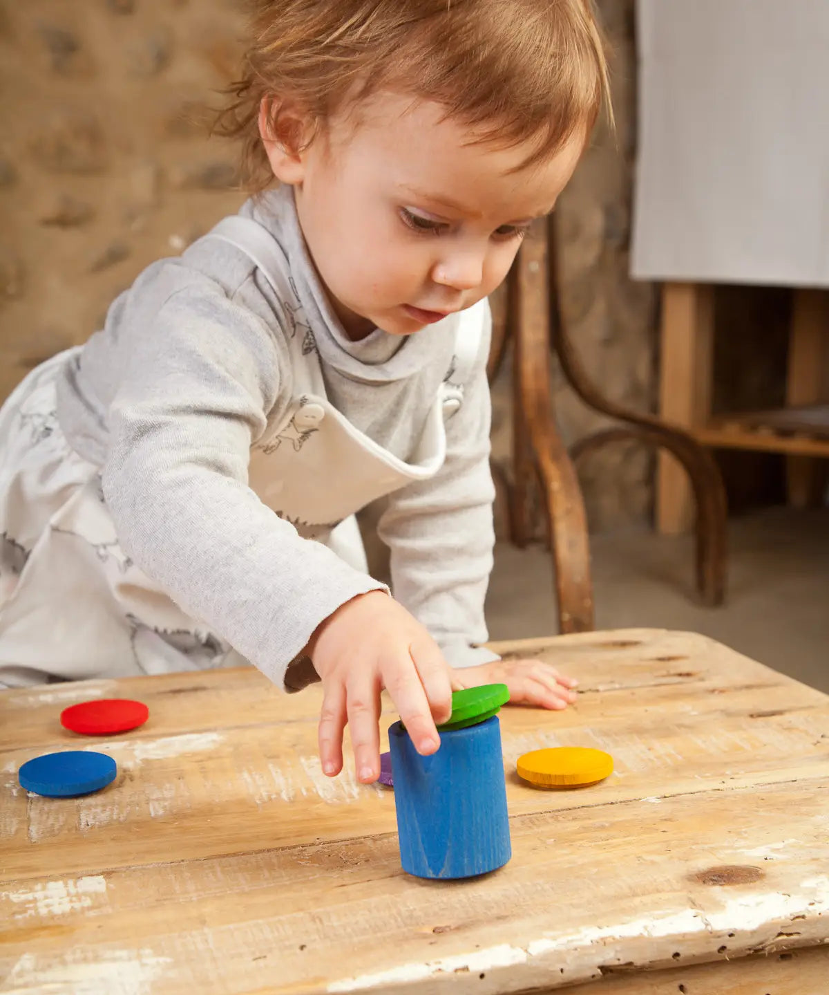 Child holding a Grapat handcrafted wooden cup with green lid on a table