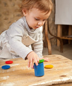 Child holding a Grapat handcrafted wooden cup with green lid on a table