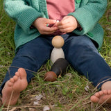 Child sitting on grass with Grapat waldorf adult wooden nin peg dolls  outdoors