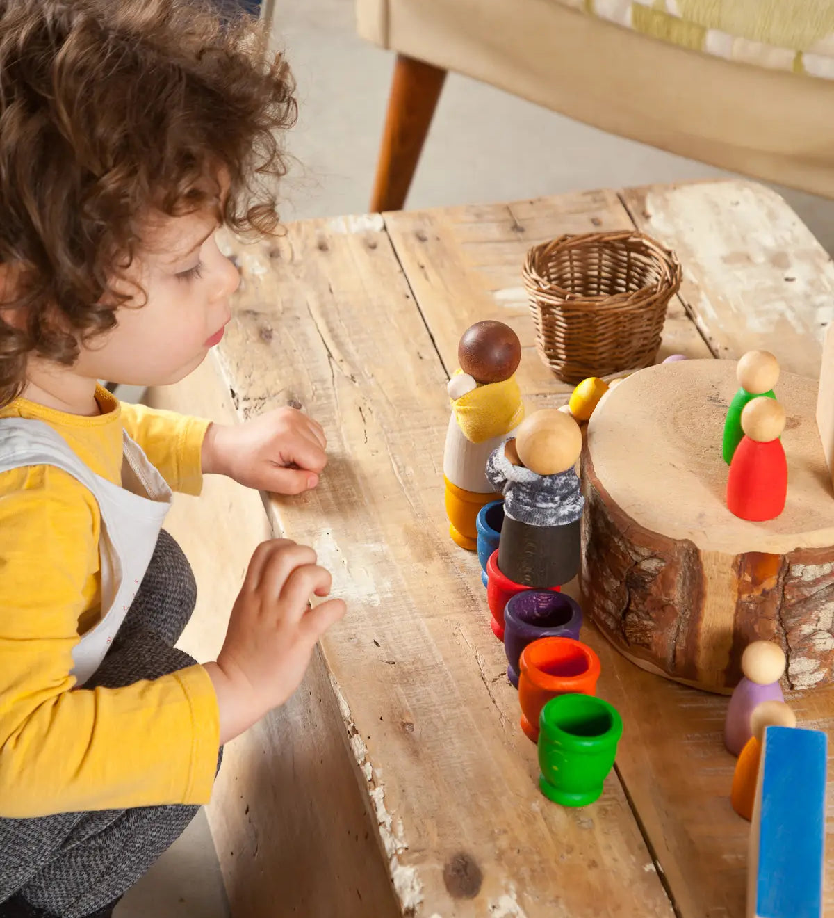 Child sitting next to a creative play setup using Grapat waldorf adult nin peg dolls 