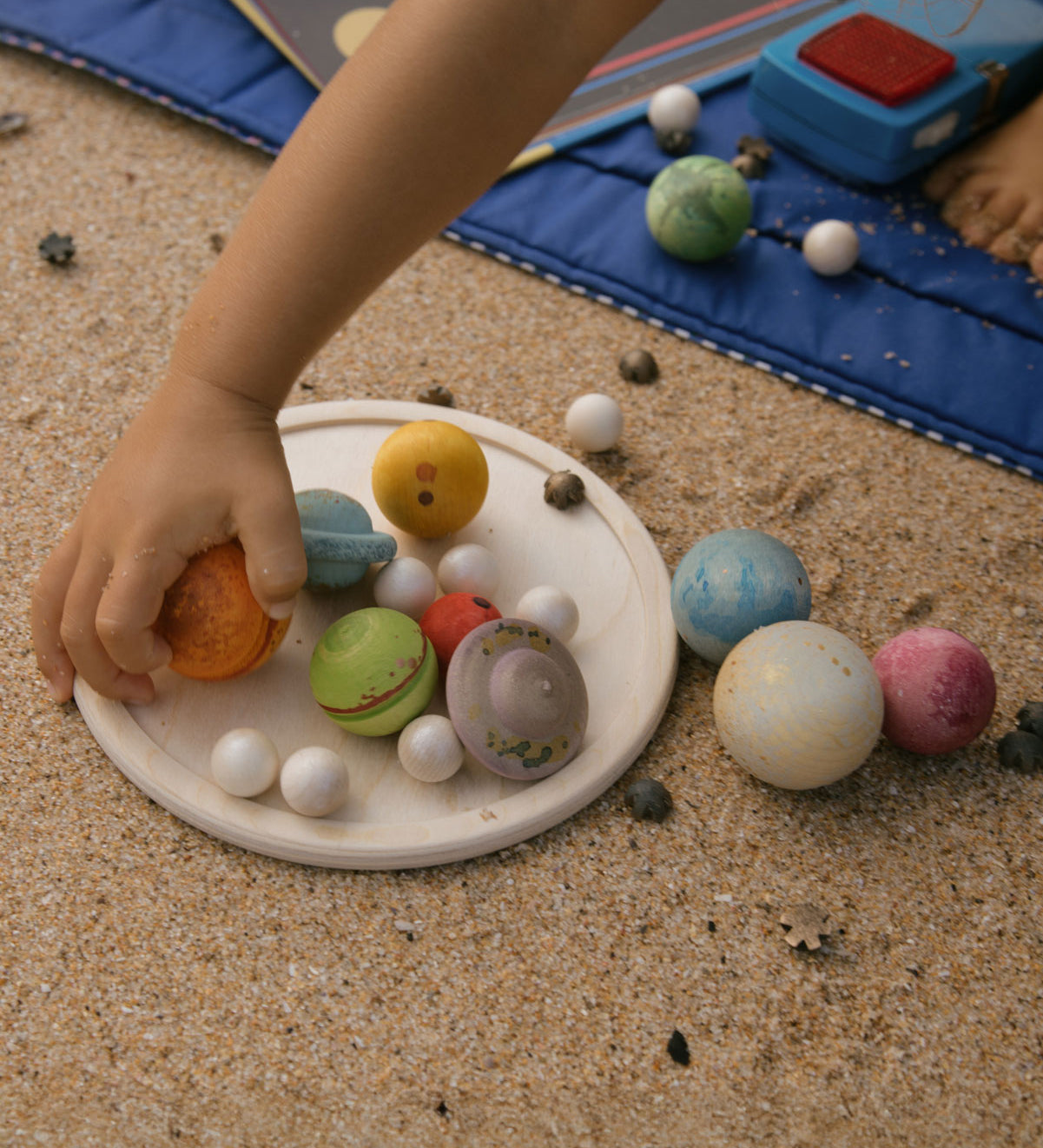 A close up of a child's hand playing with pieces from the Grapat Dear Universe Play Set.