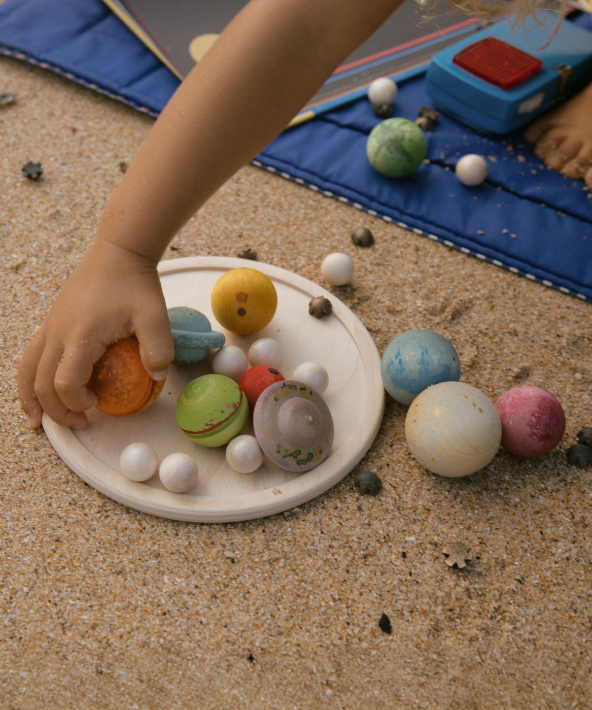 A close up of a child's hand playing with pieces from the Grapat Dear Universe Play Set.
