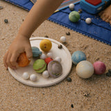 A close up of a child's hand playing with pieces from the Grapat Dear Universe Play Set.