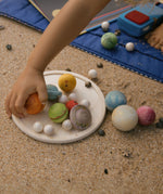 A close up of a child's hand playing with pieces from the Grapat Dear Universe Play Set.