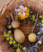 Grapat handmade Wooden Easter Decorations Hop bunny and Peep chick. The decorations have been placed in a round wicker basket with flowers.
