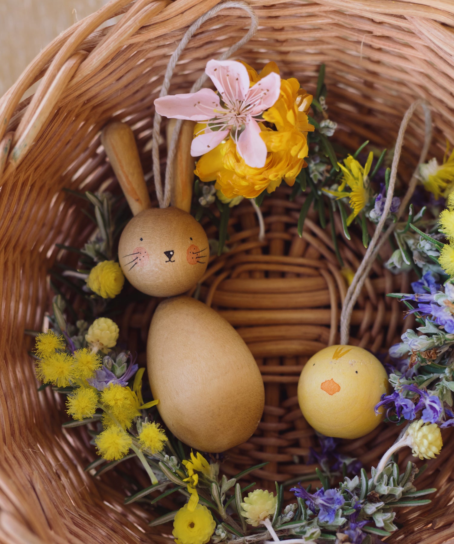 Grapat handmade Wooden Easter Decorations Hop bunny and Peep chick. The decorations have been placed in a round wicker basket with flowers.