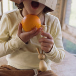 A child holding the Hop bunny decoration from the Grapat handmade Wooden Easter Decorations Hop bunny and Peep chick set.