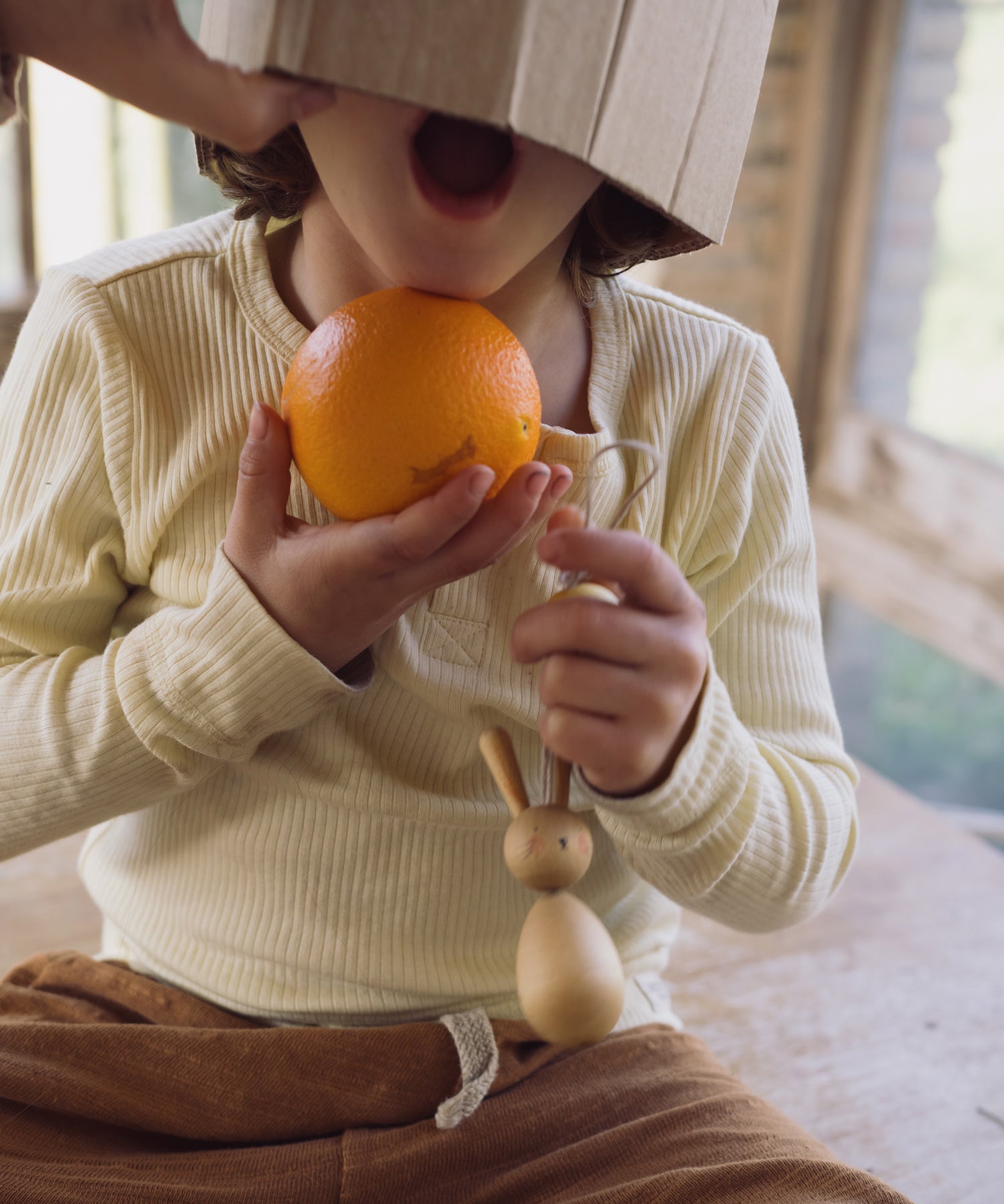 A child holding the Hop bunny decoration from the Grapat handmade Wooden Easter Decorations Hop bunny and Peep chick set.