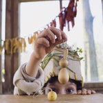 A child holding up the bunny from the Grapat handmade Wooden Easter Decorations Hop bunny and Peep chick set. The chick can be seen placed on a wooden table in front of them. 