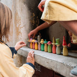 Grapat Fancy Nins Play Set. A set of 12 colourful wooden peg dolls with removable hats. These wooden peg doll toys are part of a wide range of open ended toys available at Babipur. 