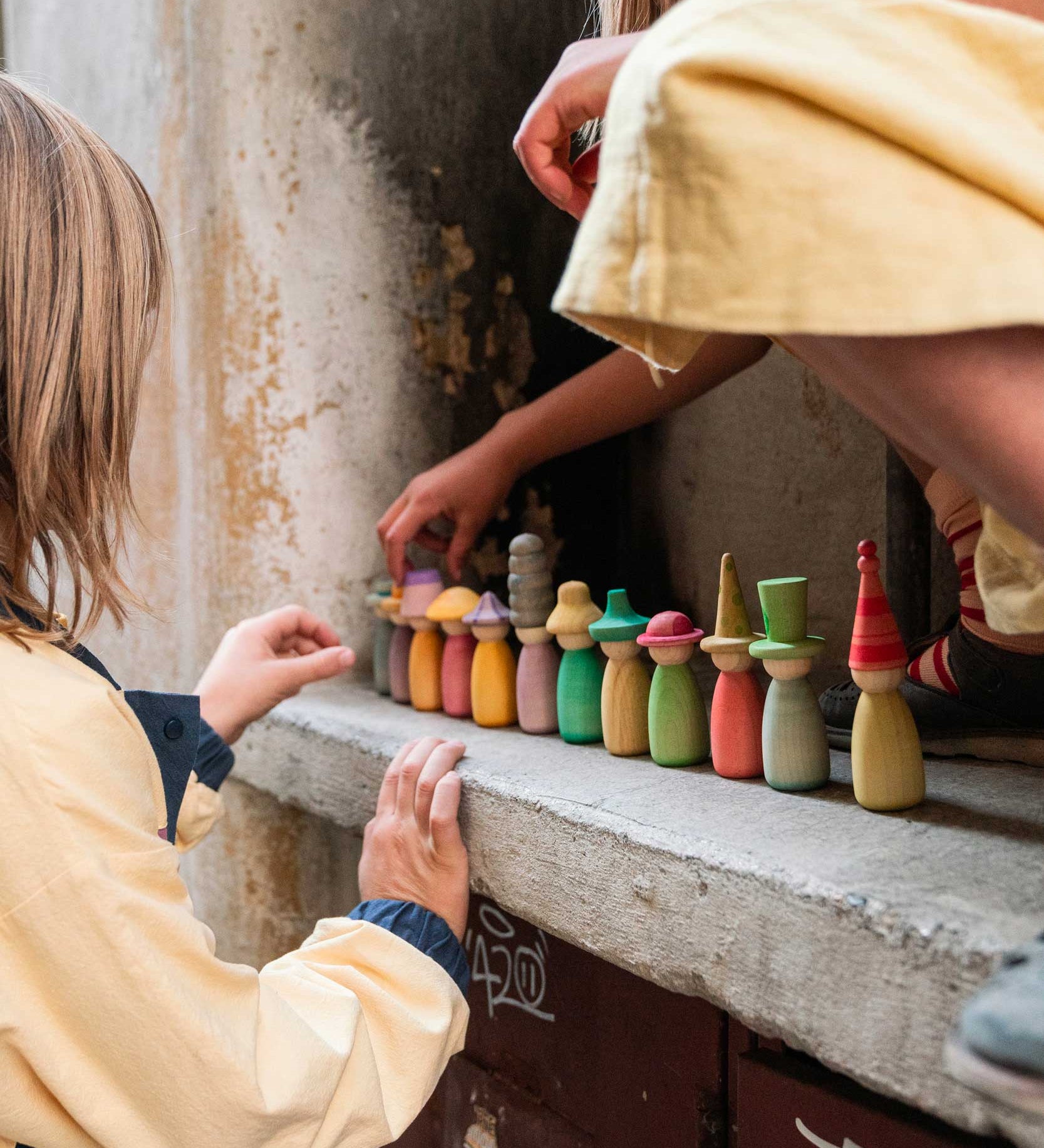 Grapat Fancy Nins Play Set. A set of 12 colourful wooden peg dolls with removable hats. These wooden peg doll toys are part of a wide range of open ended toys available at Babipur. 