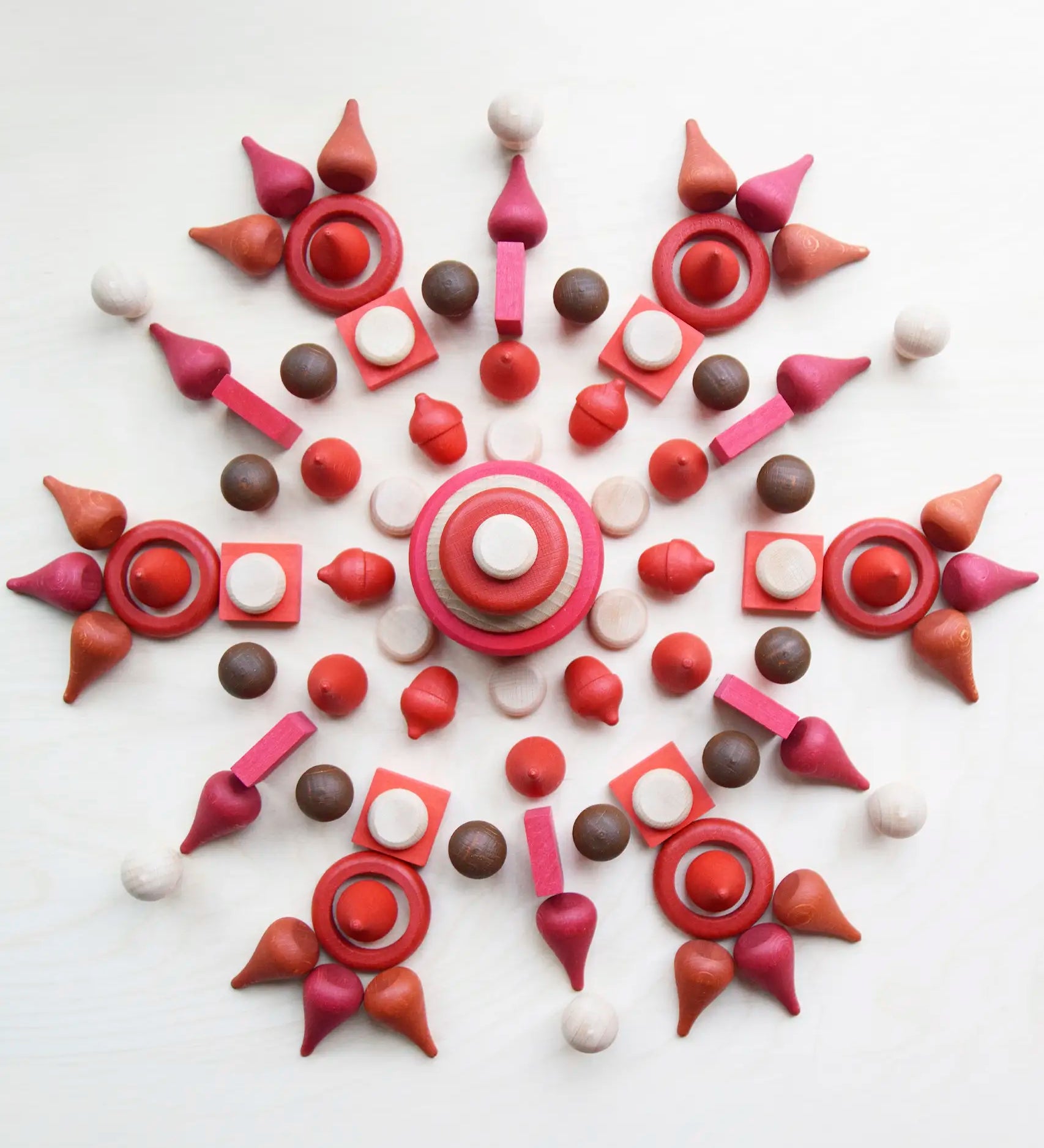 A mandala flatlay made from different Grapat wooden loose pieces in red, white and brown