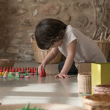 Child sorting individual Grapat fire mandala wooden pieces on a concrete surface
