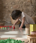 Child sorting individual Grapat fire mandala wooden pieces on a concrete surface