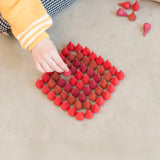 Child sorting individual Grapat wooden fire mandala droplet shaped pieces in a diamond shape