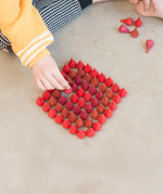 Child sorting individual Grapat wooden fire mandala droplet shaped pieces in a diamond shape