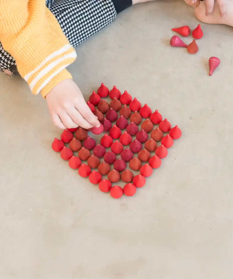 Child sorting individual Grapat wooden fire mandala droplet shaped pieces in a diamond shape
