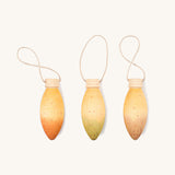 light purple, orange and green wooden Grapat glow lamps on a cream background.