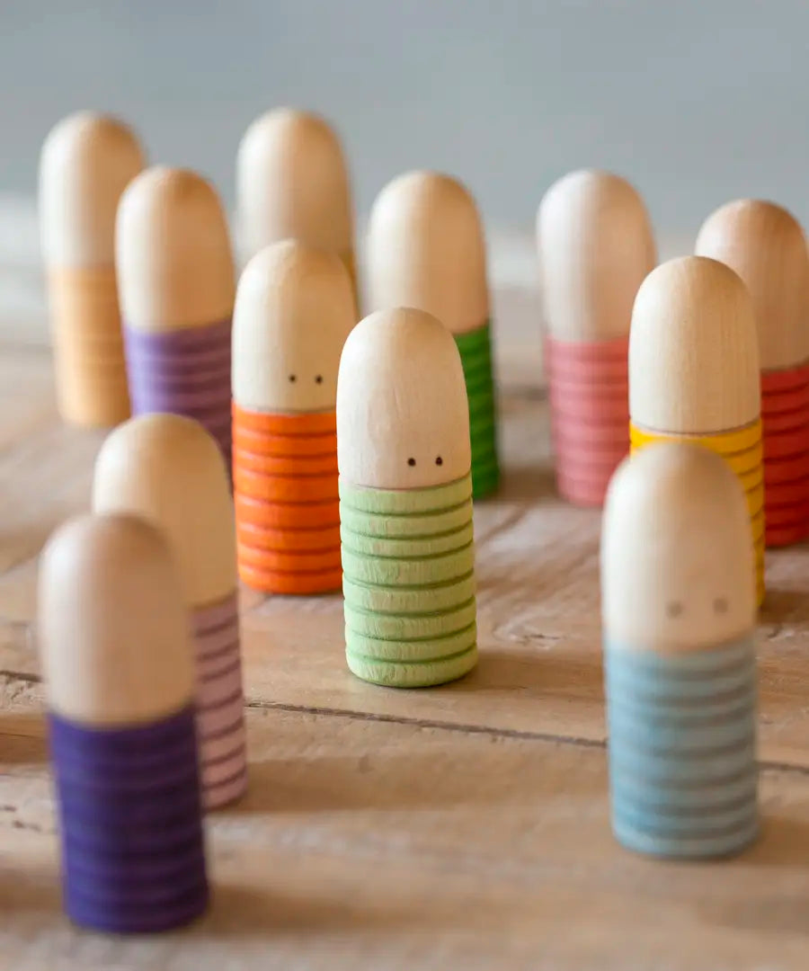 A bunch of Grapat hand crafted wooden brot peg dolls standing on a wooden surface