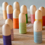 A bunch of Grapat hand crafted wooden brot peg dolls standing on a wooden surface