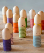 A bunch of Grapat hand crafted wooden brot peg dolls standing on a wooden surface