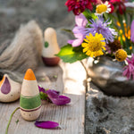 Close up of the Grapat plastic-free ooh lala toy figures on a wooden plank next to a jar of purple and yellow flowers