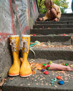 Close up of some Grapat rainbow wooden mandala flower toys scattered next to some yellow wellington boots on some stairs