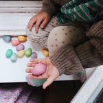 a child holding pink grapat wooden egg