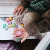 a child holding pink grapat wooden egg