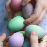Children's hand picking up Grapat Happy Eggs wooden toys. Speckled eggs in various colours.