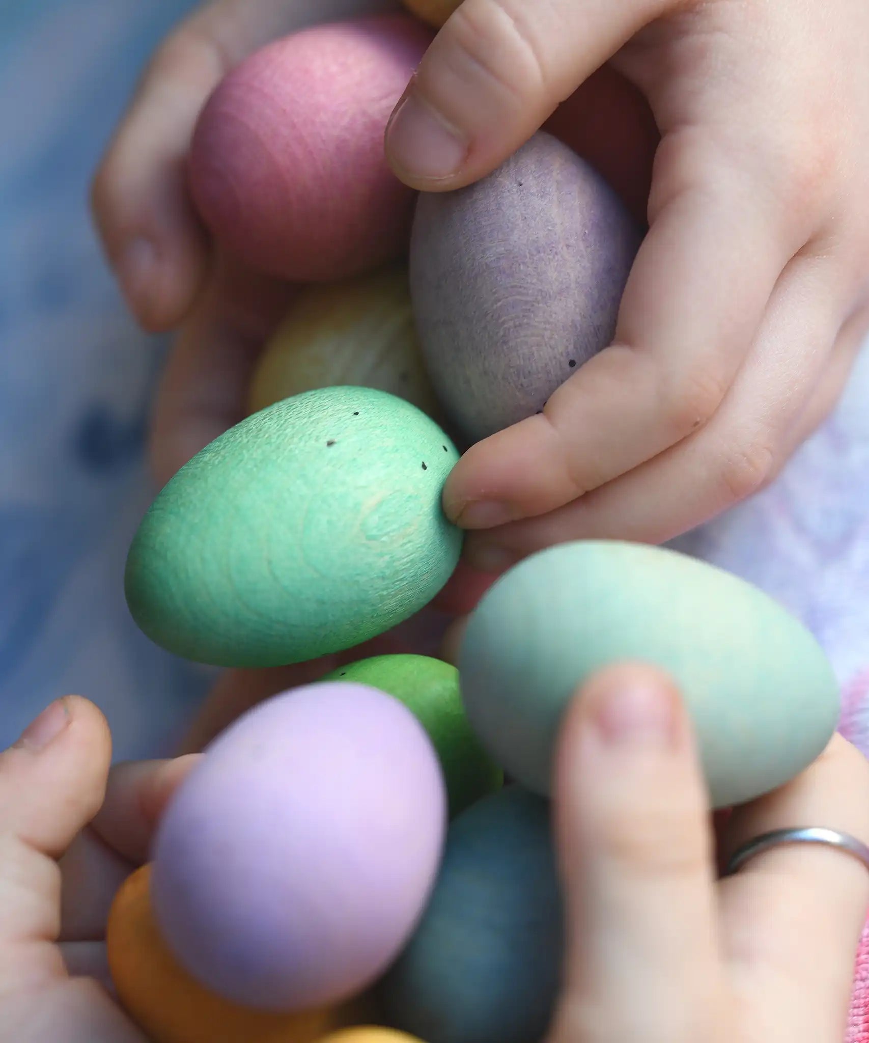 Children's hand picking up Grapat Happy Eggs wooden toys. Speckled eggs in various colours.