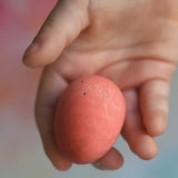 Red Grapat Happy Eggg wooden toy in a child's hand.