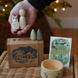 Grapat x Ostheimer Hello Winter limited edition wooden toy play set. An adult's hand is holding the Ostheimer owl and Grapat peg doll. These limited edition sets are available here at Babipur. 