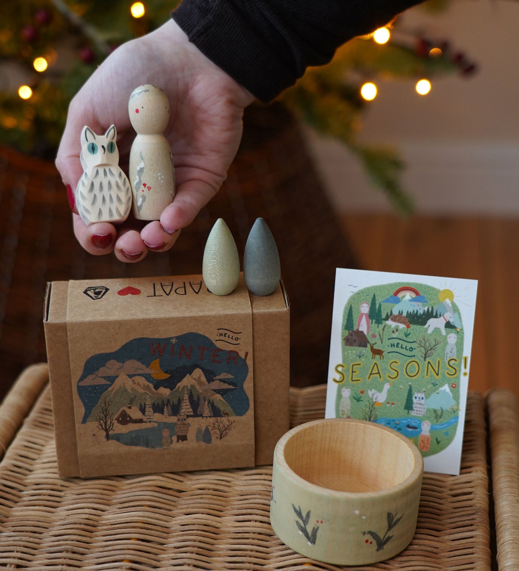 Grapat x Ostheimer Hello Winter limited edition wooden toy play set. An adult's hand is holding the Ostheimer owl and Grapat peg doll. These limited edition sets are available here at Babipur. 