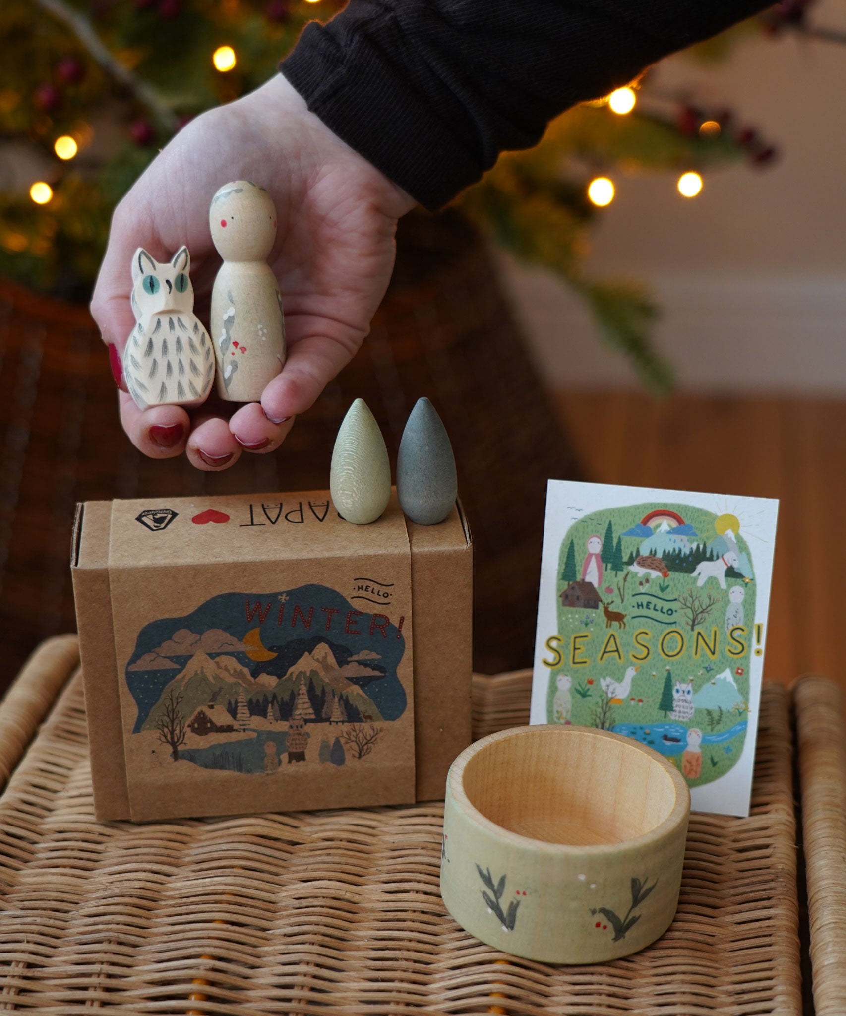 Grapat x Ostheimer Hello Winter limited edition wooden toy play set. An adult's hand is holding the Ostheimer owl and Grapat peg doll. These limited edition sets are available here at Babipur. 