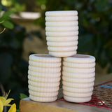 Three Grapat natural honeycomb cups stacked on a stool outdoors in the Babipur garden.
