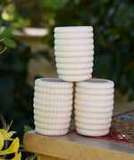 Three Grapat natural honeycomb cups stacked on a stool outdoors in the Babipur garden.