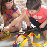 Grapat Nins® and Houses Set including 6 colourful Nin peg people and 6 coordinating colour abstract houses. Children creating a play scene using the Nins and houses and coloured ribbon. Great for colour matching and imaginary play. Two children and a ston
