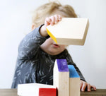 Grapat Six Wooden Houses Set in play with toddler stacking. Different simple geometric shapes in natural wood and colourful painted roofs. White background.