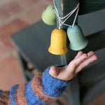 A light blue, yellow and green Grapat wooden jingle joy bells hanging on a chair