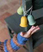 A light blue, yellow and green Grapat wooden jingle joy bells hanging on a chair
