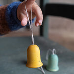A close up of the yellow wooden Grapat jingle joy bells hanging on a child's finger