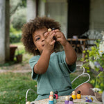 Close up of young child holding up some Grapat baby wooden peg doll toys