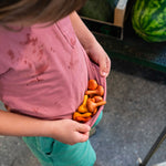 Close up of child cupping some Grapat handmade wooden mandala pumpkins in their t-shirt