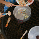 Children are using the Grapat Wooden Sensory Play Tools to make a meal. One child is pouring in lentils