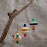 Grapat kind folk wooden Christmas ornaments hanging decorations, three hand painted wooden decorations hung on a branch.